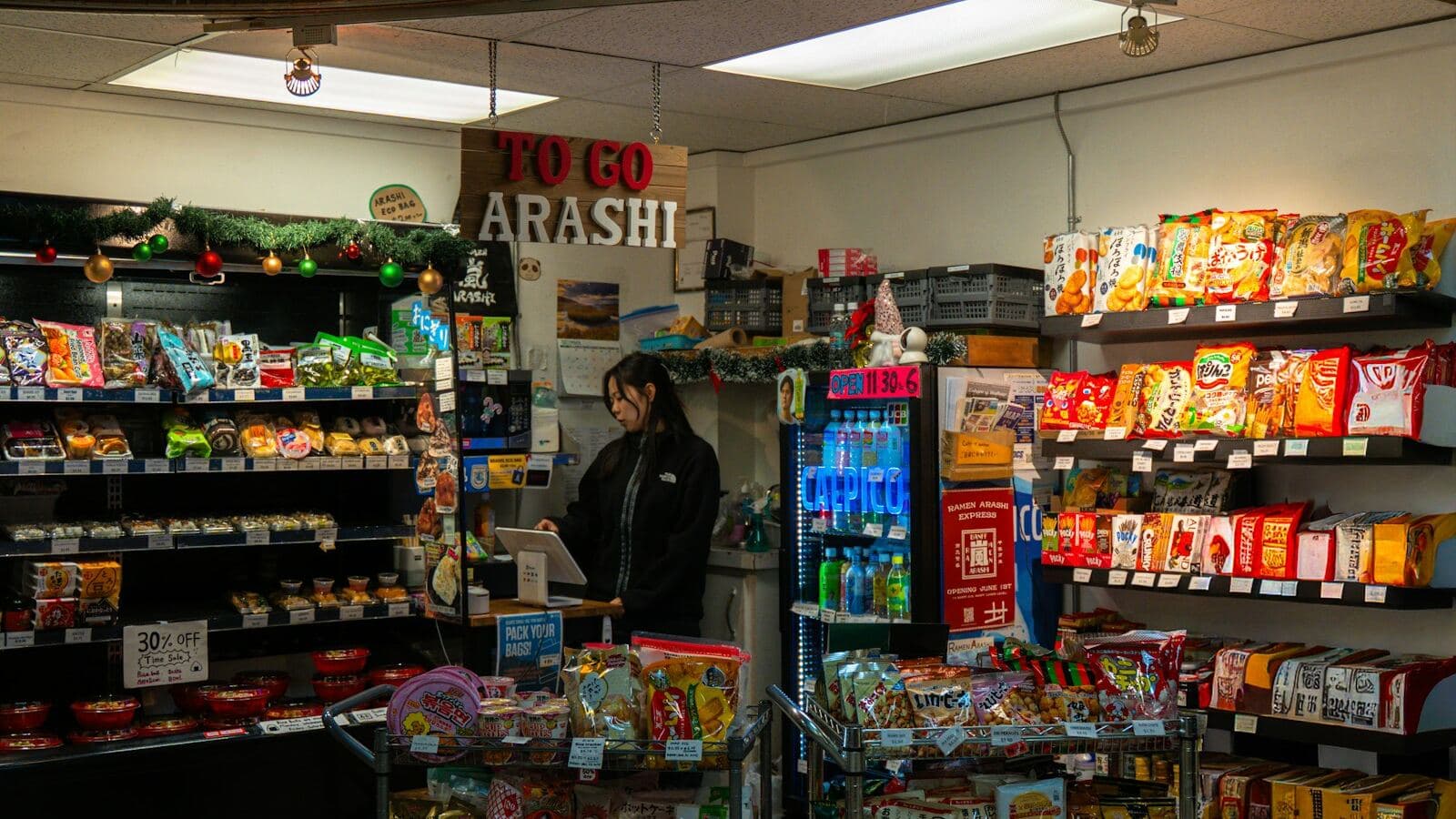 Open self-serve market shelving stocked with snacks and drinks