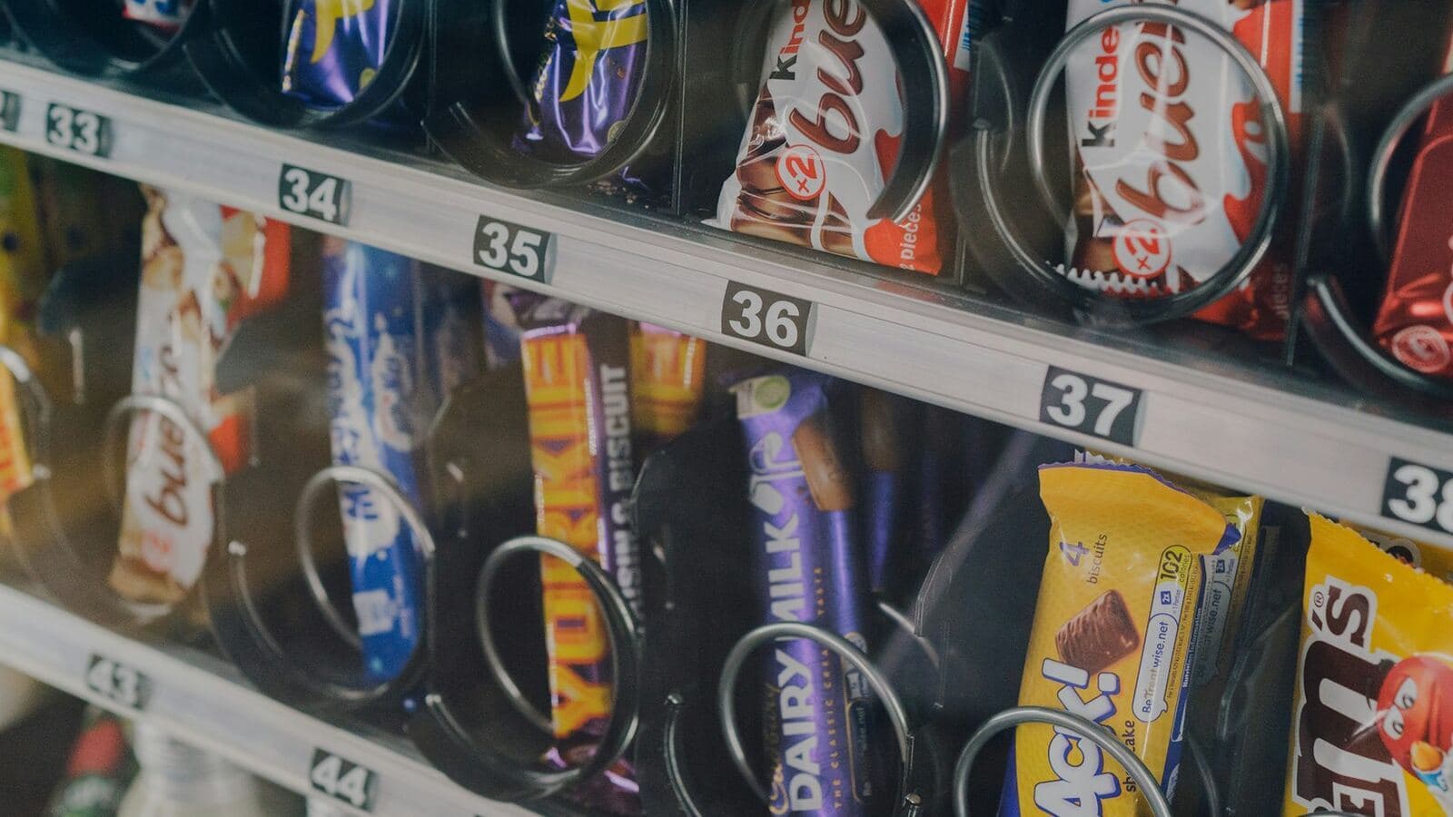 Close-up of a glass-front vending machine stocked with snacks and priced selection tags